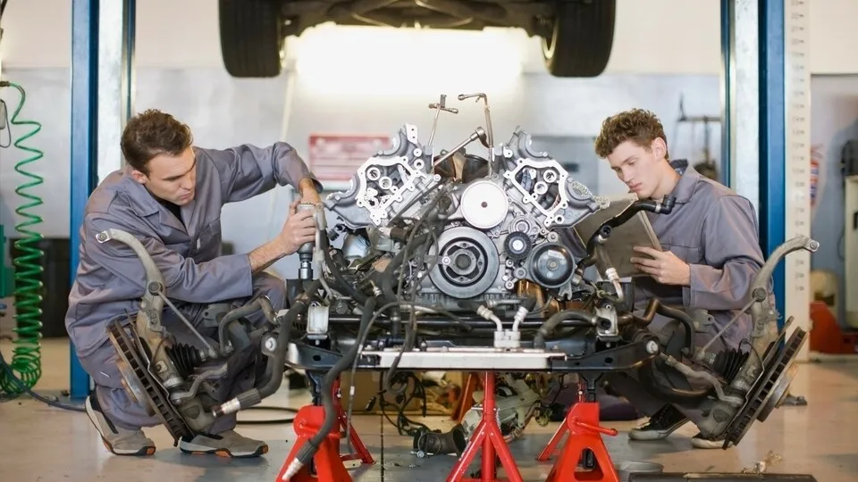 Mechanics working on car engine --- Image by © Zero Creatives/cultura/Corbis